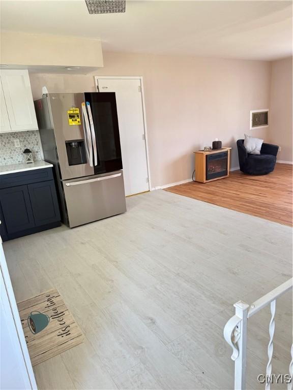 kitchen with light countertops, visible vents, stainless steel refrigerator with ice dispenser, and light wood-type flooring