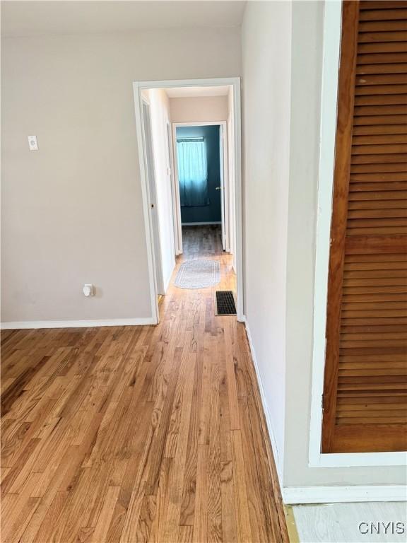 hall with light wood-type flooring, baseboards, and visible vents
