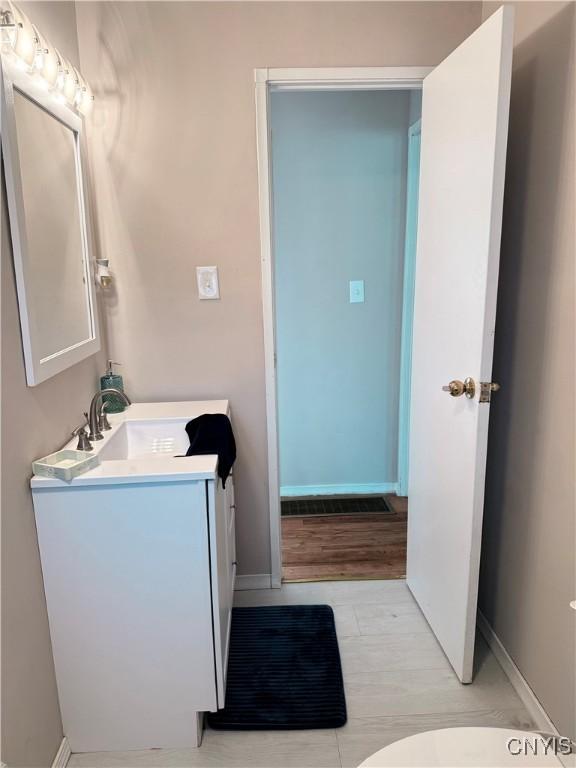 bathroom featuring vanity, wood finished floors, and baseboards