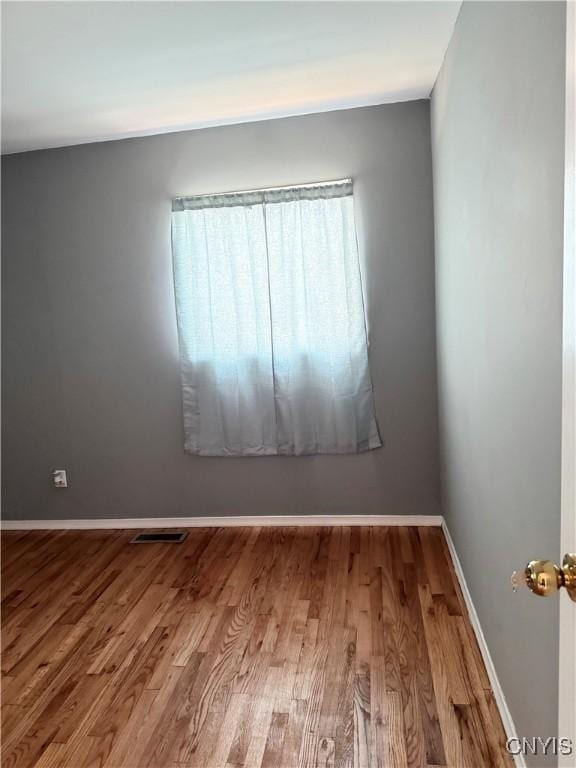 spare room with visible vents, baseboards, and wood finished floors