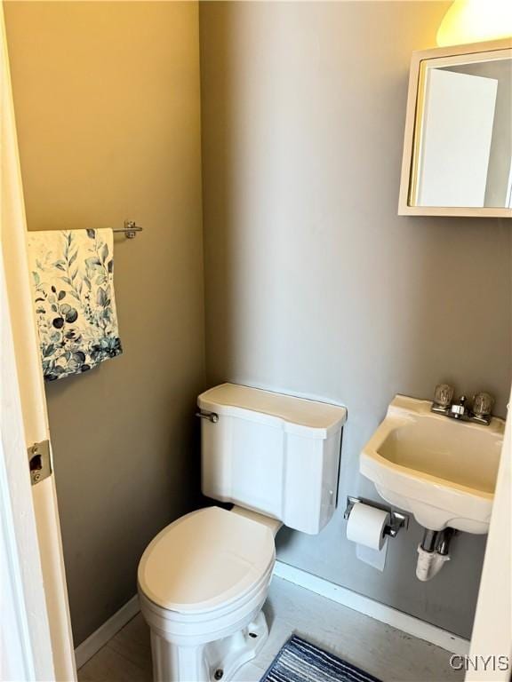 bathroom featuring a sink, baseboards, and toilet