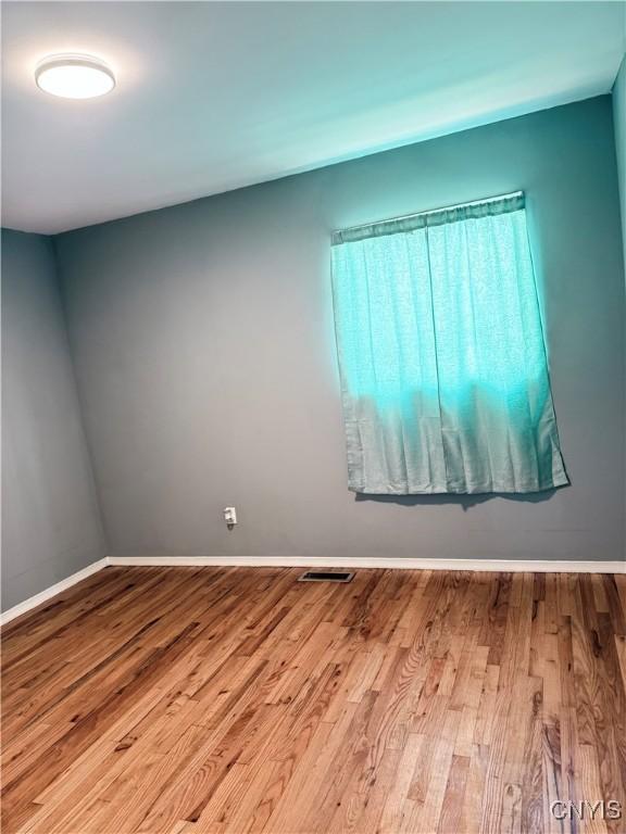 spare room with visible vents, baseboards, and wood finished floors