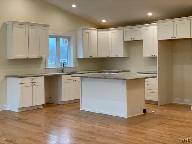 kitchen with white cabinetry, a center island, and sink