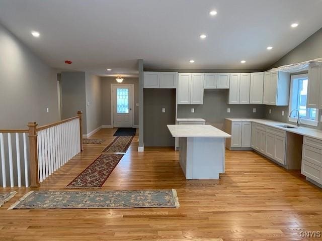 kitchen with a wealth of natural light, white cabinetry, sink, a center island, and light wood-type flooring