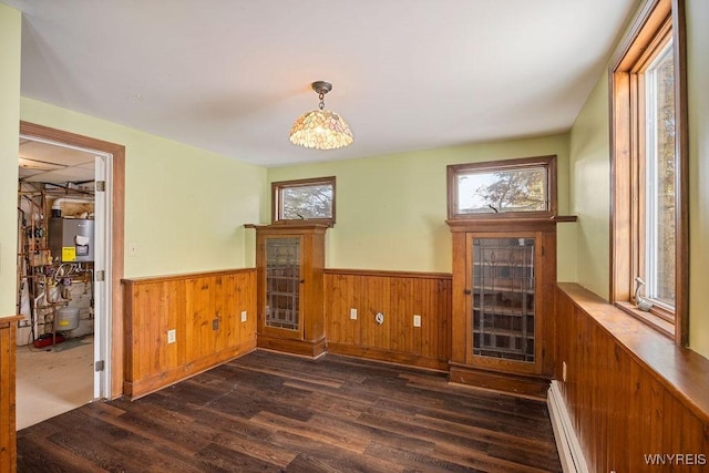 2202 River Rd, Wheatfield, NY 14304 - unfurnished dining area featuring dark wood-style flooring, wainscoting, a baseboard radiator, a fireplace, and wooden walls