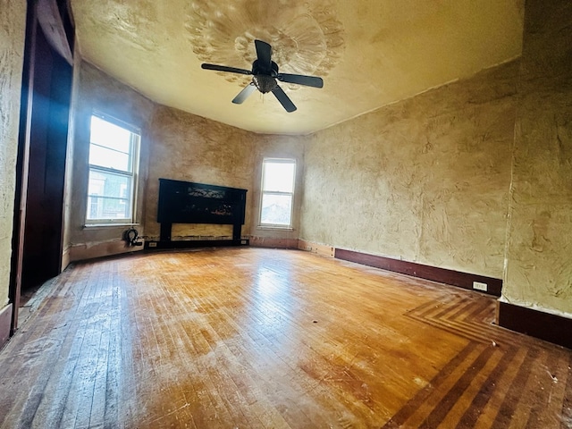 unfurnished living room with hardwood / wood-style flooring, ceiling fan, and a healthy amount of sunlight