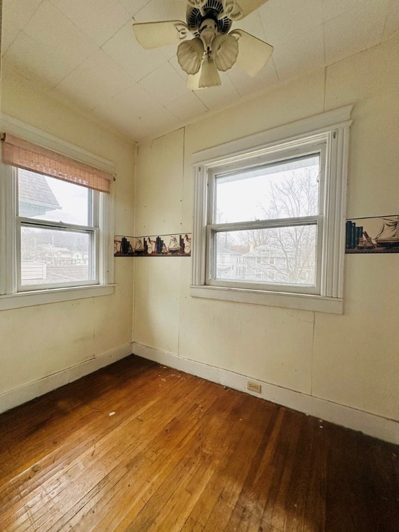 unfurnished room featuring hardwood / wood-style flooring, ceiling fan, and a healthy amount of sunlight