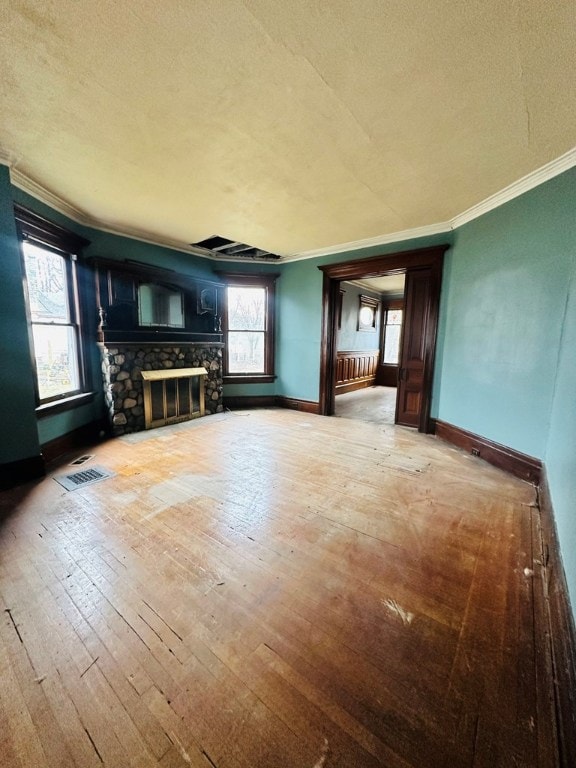 unfurnished living room with a textured ceiling, a fireplace, ornamental molding, and wood-type flooring