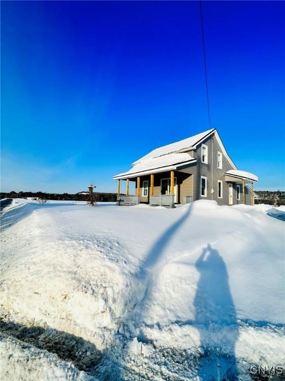 snow covered rear of property featuring a porch