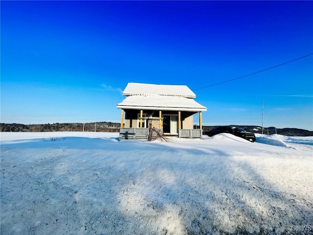 snow covered back of property featuring a porch