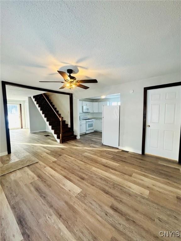 unfurnished living room with ceiling fan, light hardwood / wood-style floors, and a textured ceiling