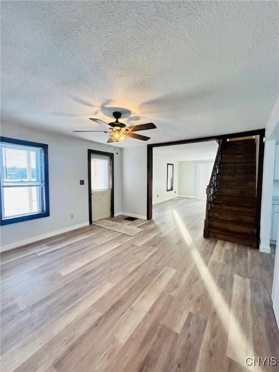 unfurnished living room with ceiling fan, light hardwood / wood-style floors, and a textured ceiling