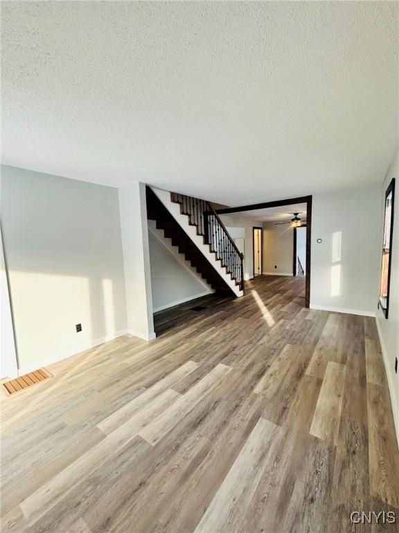 unfurnished living room with wood-type flooring and a textured ceiling