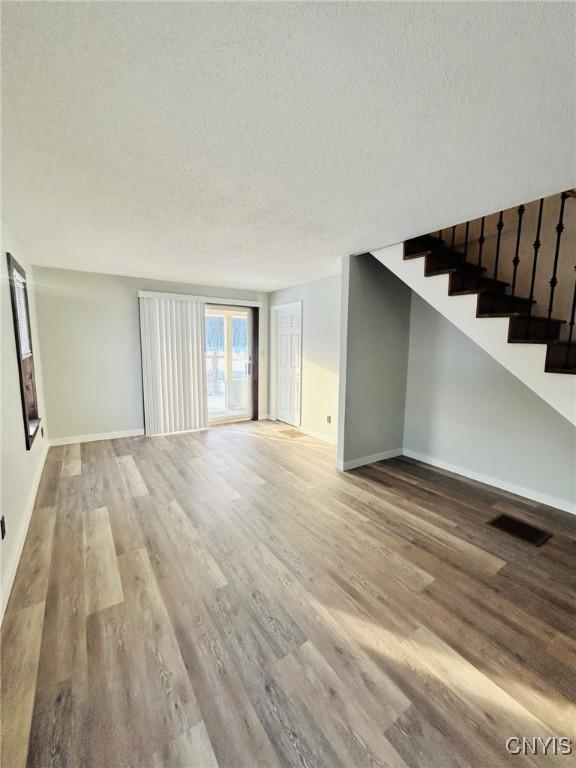 unfurnished living room with a textured ceiling and light hardwood / wood-style flooring