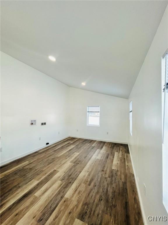 spare room with hardwood / wood-style flooring and vaulted ceiling