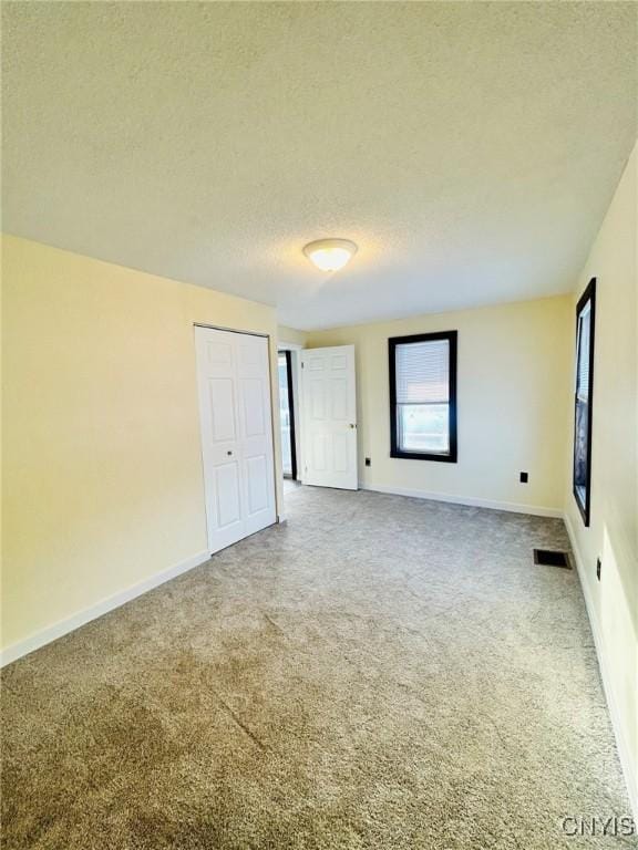 carpeted empty room featuring a textured ceiling