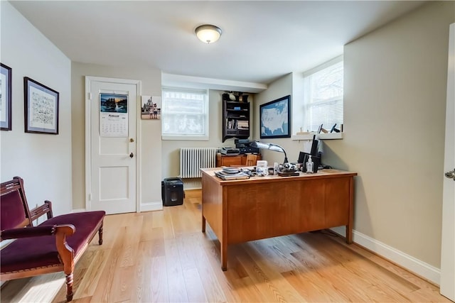 home office featuring radiator, a wealth of natural light, and light wood-type flooring