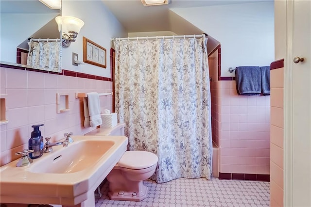 full bathroom featuring shower / bath combination with curtain, toilet, sink, and tile walls