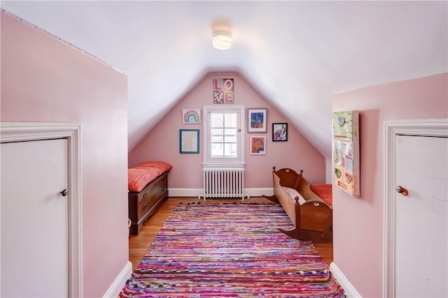 interior space with hardwood / wood-style floors, lofted ceiling, and radiator heating unit