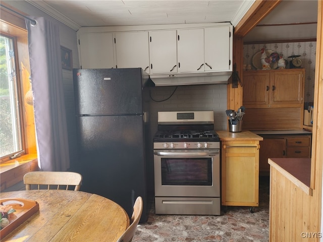 kitchen with stainless steel gas stove, white cabinetry, a wealth of natural light, and black fridge