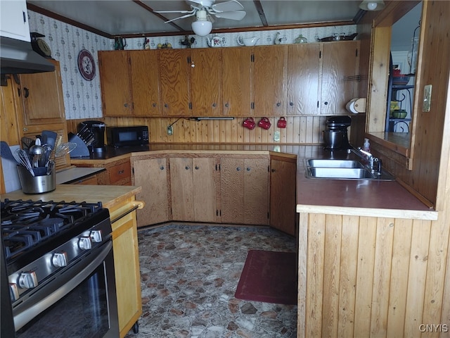 kitchen featuring sink, stainless steel gas range, exhaust hood, and ceiling fan