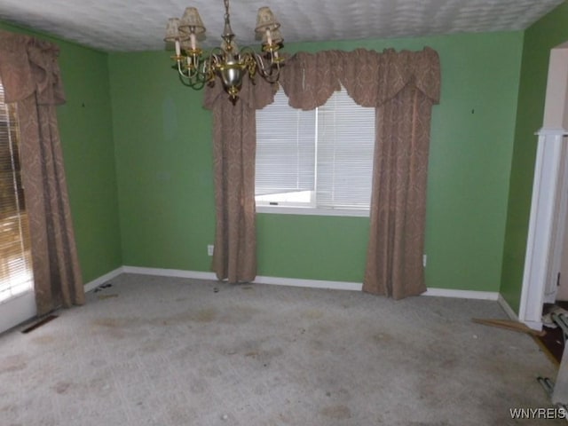 spare room featuring light carpet, a textured ceiling, and a chandelier