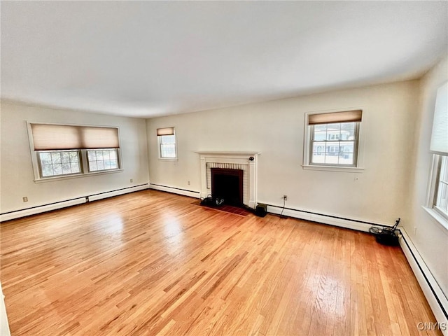 unfurnished living room with a baseboard heating unit, a fireplace, and light wood-type flooring