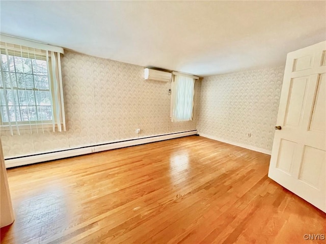 unfurnished room with light wood-type flooring, a wall mounted AC, and baseboard heating