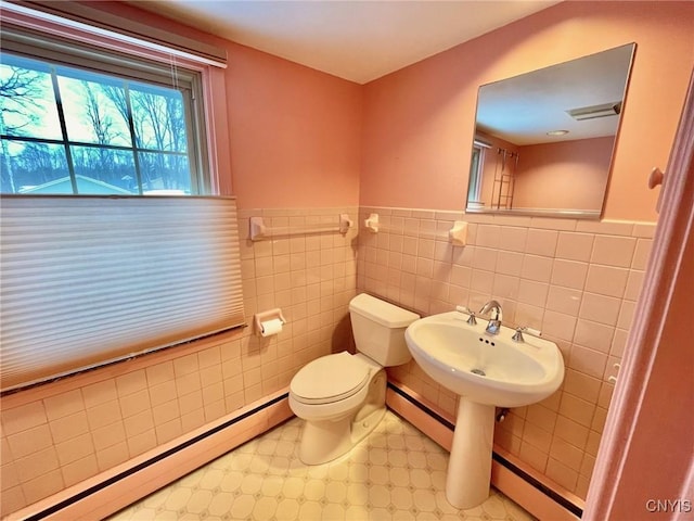 bathroom featuring tile walls, a baseboard radiator, and toilet