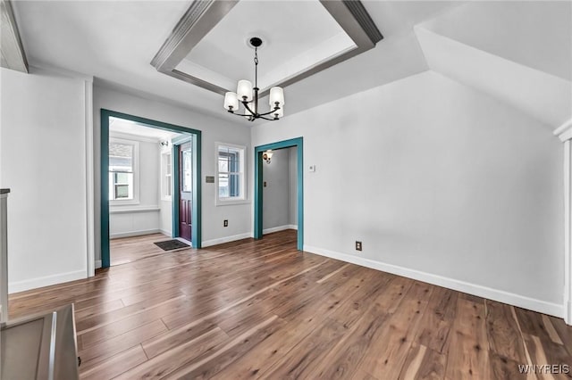 unfurnished dining area with an inviting chandelier, wood-type flooring, and a raised ceiling