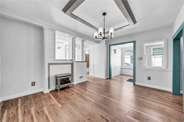 unfurnished living room with a raised ceiling, wood-type flooring, and a chandelier