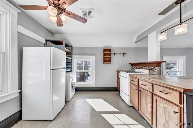 kitchen with white appliances, washer / dryer, hanging light fixtures, and a wealth of natural light