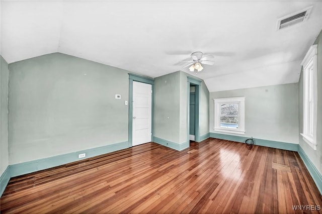 empty room with lofted ceiling, wood-type flooring, and ceiling fan