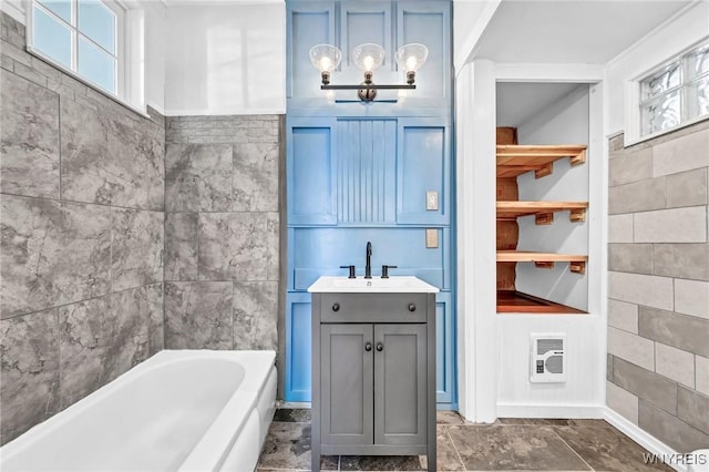 bathroom with tile walls, vanity, a bathtub, and heating unit