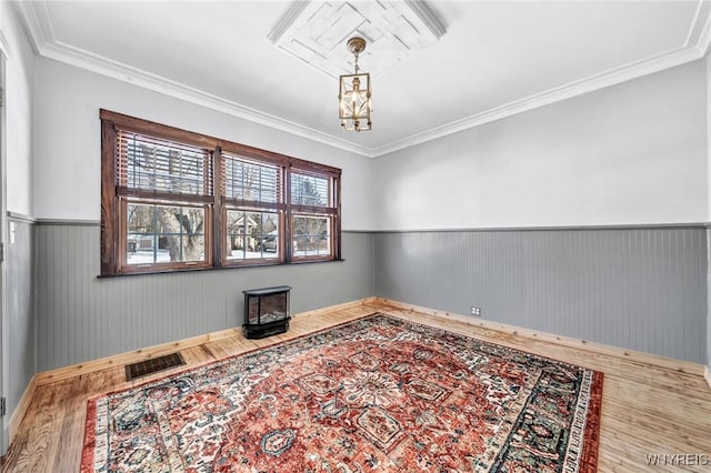 unfurnished room featuring hardwood / wood-style flooring, ornamental molding, and an inviting chandelier