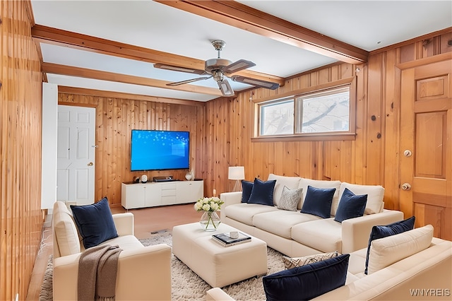 living room with beamed ceiling, ceiling fan, and wood walls