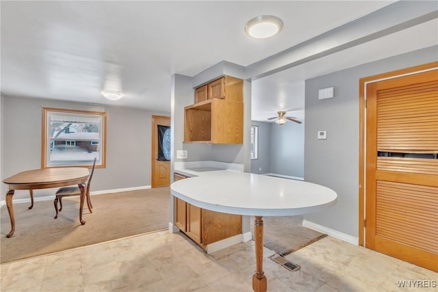 kitchen featuring ceiling fan, light colored carpet, light brown cabinetry, and kitchen peninsula