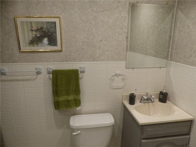 bathroom with vanity, toilet, and tile walls