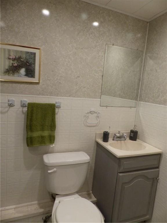 bathroom with vanity, tile walls, and toilet