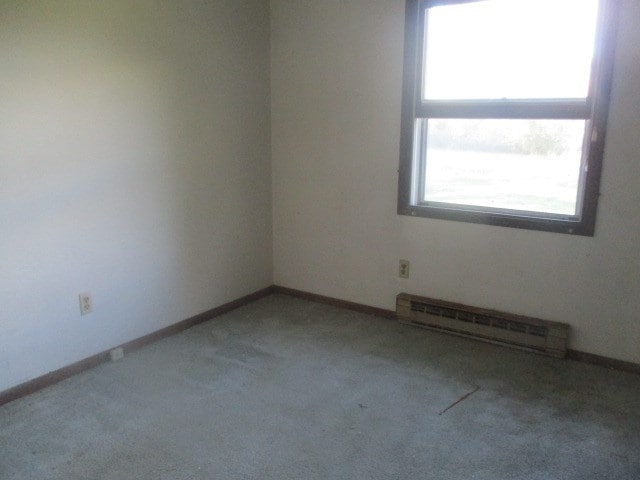 carpeted empty room with a baseboard radiator