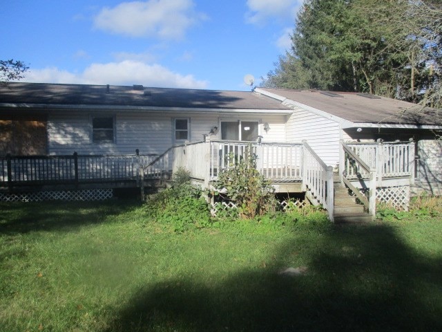 back of property with a yard and a deck