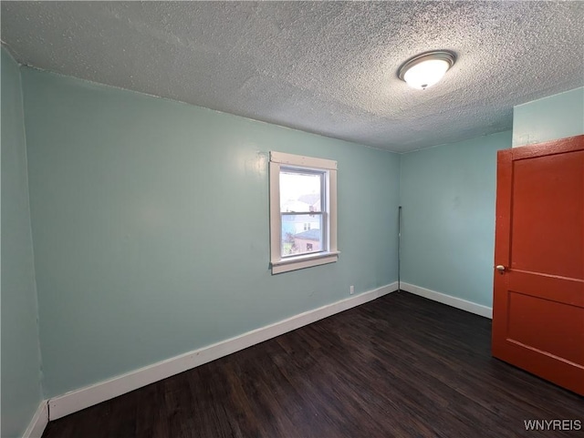 spare room with dark wood-type flooring and a textured ceiling