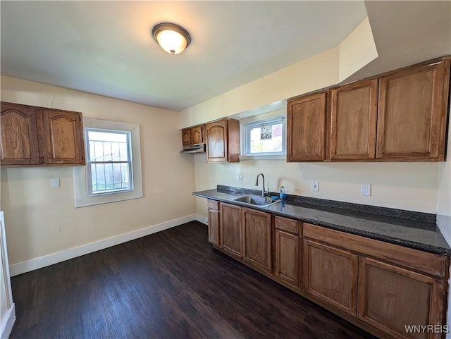 kitchen featuring sink, dark hardwood / wood-style floors, and dark stone counters