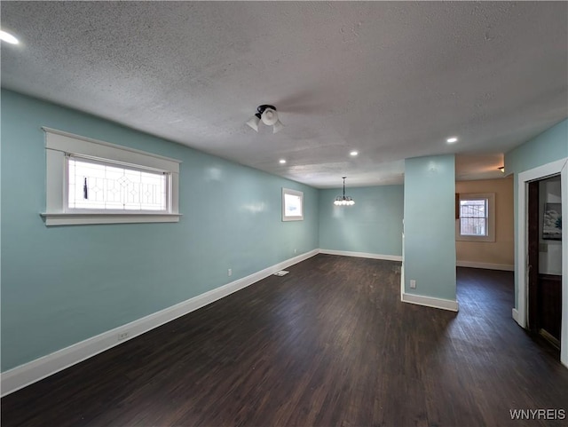 basement with dark wood-type flooring, a chandelier, and a textured ceiling