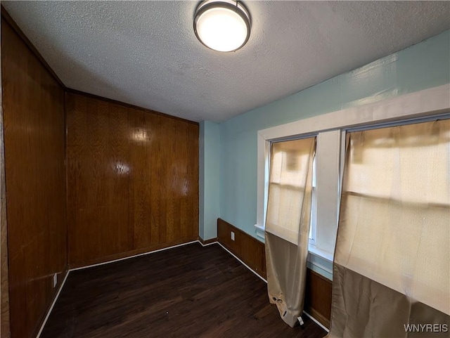 interior space featuring dark hardwood / wood-style flooring, a textured ceiling, and wood walls