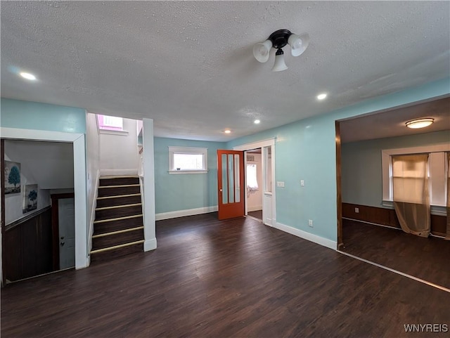 unfurnished living room featuring dark wood-type flooring and a textured ceiling