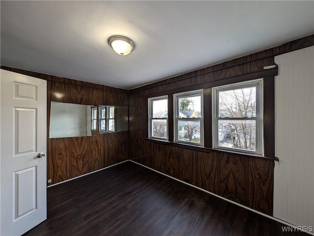 spare room with dark hardwood / wood-style flooring and wooden walls