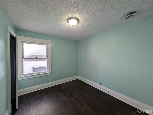 spare room with dark wood-type flooring and a textured ceiling