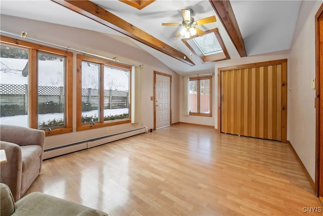 interior space featuring a baseboard heating unit, vaulted ceiling with skylight, ceiling fan, and light hardwood / wood-style flooring