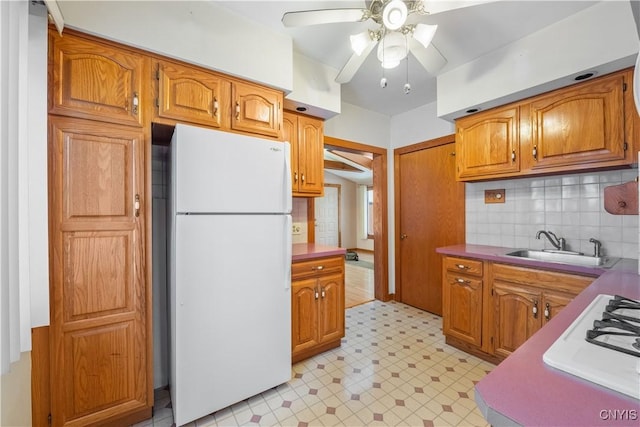 kitchen with tasteful backsplash, sink, white refrigerator, ceiling fan, and gas stovetop